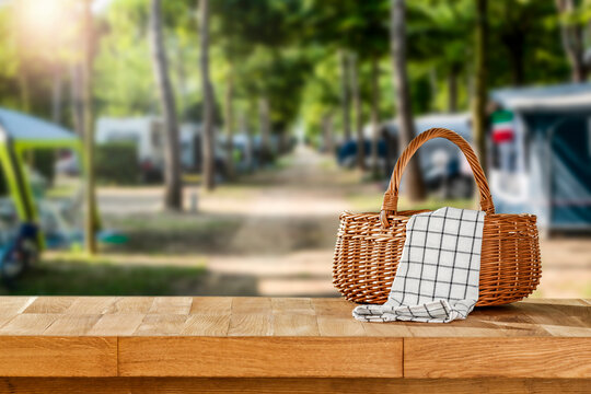 Wooden table with wicker basket for camping on a sunny holiday day. 