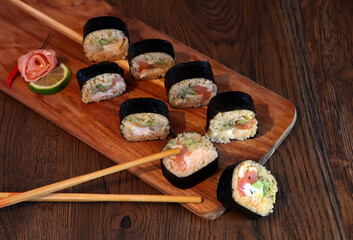 hot roll set sashimi japanese food on wooden background with lemon and chopsticks
