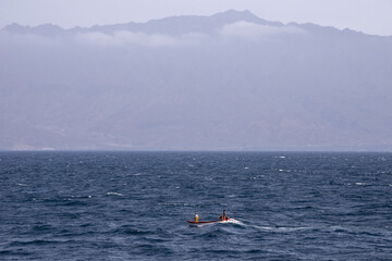 Barca de pesca navegando en la bahía de Mindelo, con la sila de Santo Antao de fondo en Cabo Verde