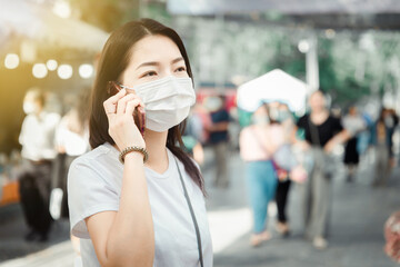 beautiful asian woman wear white mask to protect against dust PM 2.5 and viruses when going out for...