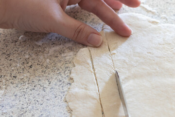 Freshly rolled dough being cut into strips to make homemade chicken and dumplings, a southern...