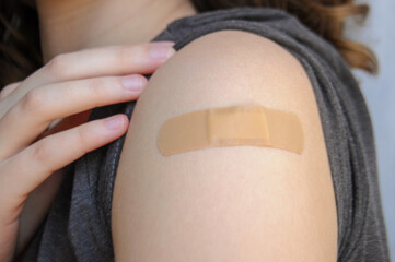 Close up on a female arm with a brown patch after vaccination for covid-19