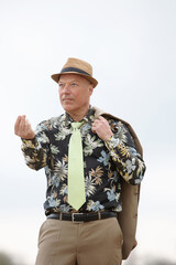 man in a suit from the 1980s and colorful shirt gestures like a classical gangster
