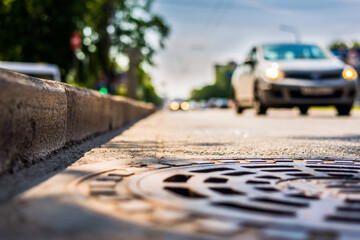 Summer in the city, the car passing by on the avenue. Close up view from the hatch level near the curb on the road