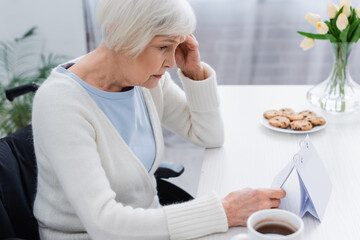 senior woman, suffering from memory loss, looking at calendar at home