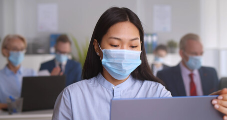 Multiethnic businesspeople wearing face masks working in office