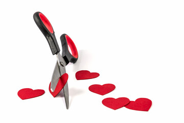 Scissors cut out decorative red hearts on a white background.