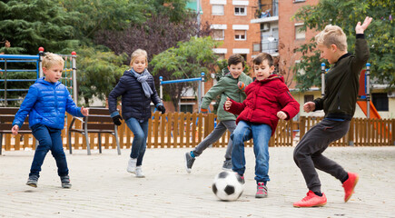 Company of kids are jogning and playing football. High quality photo