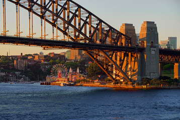 The setting sun casts a warm glow on the Sydney Harbour bridge and cityscape at Darling Harbour in Sydney, Australia.
