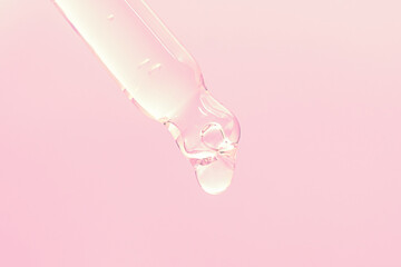 face serum drop with glass dropper pipette on pink background close up macro