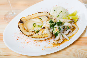 Dish of Mediterranean cuisine - baked in oven cuttlefish, rice, lemon and parsley