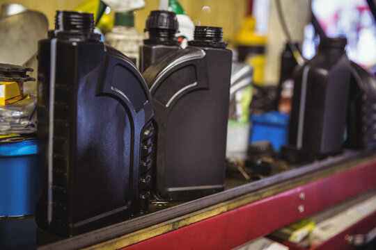 Plastic bottles of motor oils and automotive fuels on shelf in workshop