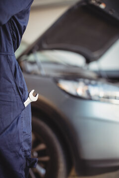 Close up on monkey wrench in the pocket of car mechanic, wearing work clothes