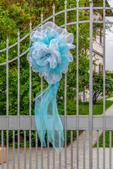 A large blue ribbon attached to the gate of a villa announces the birth of a newborn baby boy in the Italian tradition