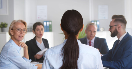 Group of business people sitting around office desk and discussing project together
