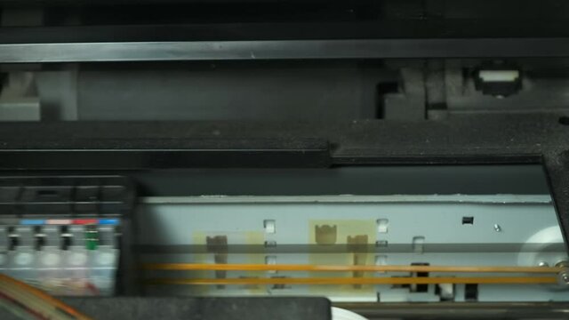 Continuous ink supply system is working in printer moving inside, closeup view. Printing new inkjet printer for launch, CISS. Small printer for use and printing at home, filled with only black paint.