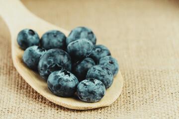 Close-up of a spoon with fresh blueberries on a rustic background.