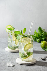 Two mojito with lime, mint, and ice cube on gray background. Close up.