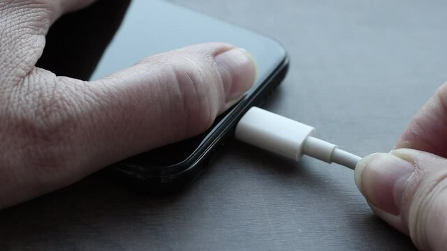 Woman plugging a USB type C cable into a smartphone connector to charge. Special charging connector for phone.