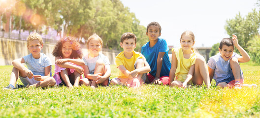 Group of happy kids on green grass in summer park