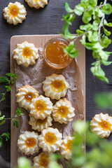 Homemade shortbread cookies qurabiya with orange jam in the center on a baking paper on grey wooden table. Top view, vertical