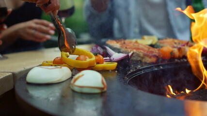 Unrecognizable women turning vegetables outside. Girls cooking vegetarian food