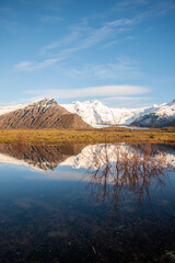 Fototapeta na wymiar Icelandic mountain range with beautiful snowcapped mountains reflected into still water.