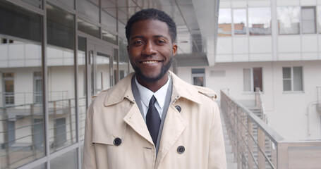 Portrait of handsome african businessman smiling outdoors office building