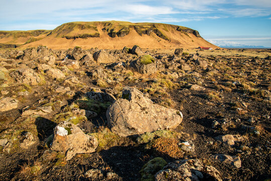 Vertical image of Icelandic topography with warm brown and orange tones and rocky texture with a blue sky