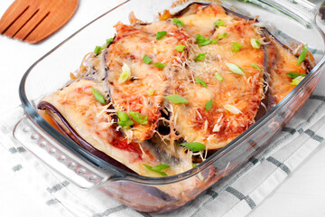 Vegetarian casserole with eggplant, parmigiano cheese and tomato sauce in the glass baking dish