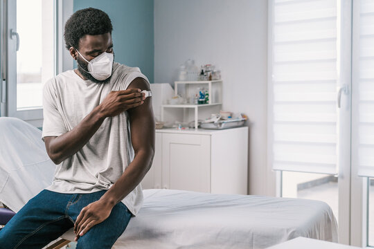 African American man patient holding cotton with alcohol disinfecting arm after covid vaccine procedure in clinic during coronavirus outbreak
