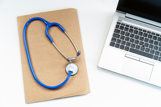 From above modern medical workspace with laptop, stethoscope and paper form document on folder on desk in hospital