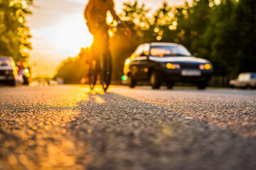 Sunset in the suburbs, the car and a bicycle traveling on the highway. Close up view from the asphalt level
