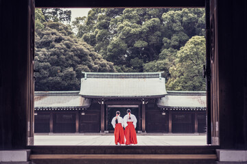 Back view of unrecognizable people in traditional kimono standing outside of ancient Meiji Shrine temple located in mountains in Shibuya in Tokyo, Japan