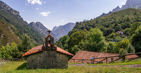 Vistas panorámicas de la Iglesia de San Esteban en Asturias, en medio de la naturaleza verde y las montañas al fondo, con un campanario en el tejado, viajando por España en el verano de 2020.