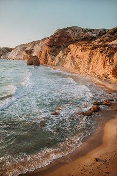 Picturesque scenery of rough stony seashore washed by waving warm sea beneath cloudless blue sky in Fyriplaka Milos on sunny weather
