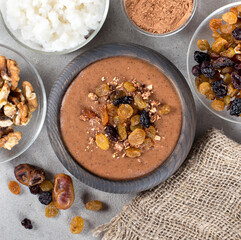 Soup puree of dried fruits, raisins, dates, nuts with cocoa in a wooden bowl on a light gray background in rustic style top view