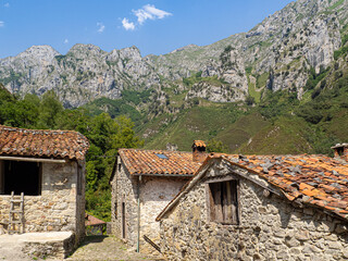 Vistas de las fachadas de unas casas rurales de piedra  con las montañas de fondo , en el pueblo de San Esteban de Cuñaba en Asturias, España, verano de 2020