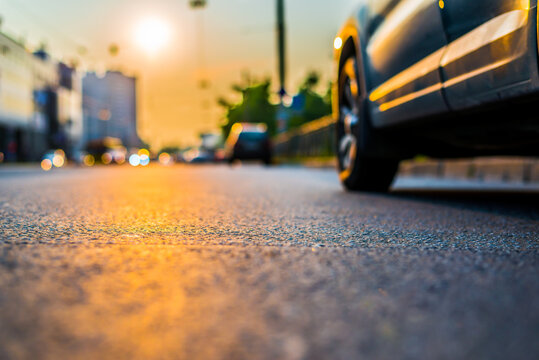 Sunset in the city, the headlights of the approaching cars. Close up view from the asphalt level