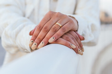Crop unrecognizable bride with manicured nails and in golden wedding ring leaning on white railing