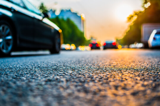 Sunset in the city, the cars traveling on the road. Close up view from the asphalt level
