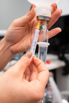 Crop unrecognizable vet with injector filling drop counter with liquid against professional equipment in hospital