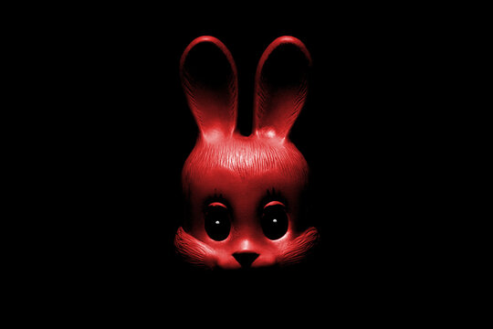The face of a red toy rabbit in the dark