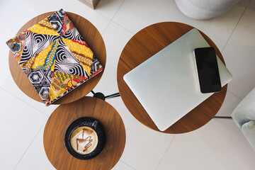 Top view of a three-part round table with a coffee, a phone, and an abstract notebook on itinterior