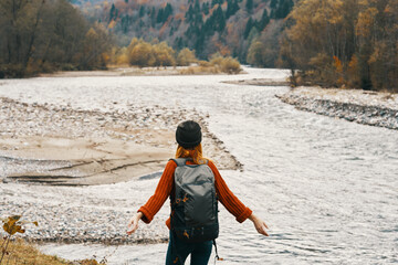 woman resting on the river bank in the mountains on nature landscape and model backpack tourism