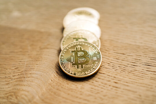 Row of similar metal crypto coins with letter on desk on shiny blurred background