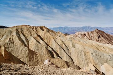 A family hike from Zabriskie Point in Death Valley national park in california. Huge sand dunes, terracotta mountains and hazy horizons are shining against clear blue sky in the midday sun.