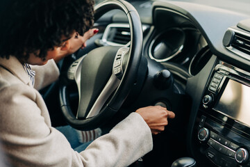 High angle of crop African American female driver starting auto engine with key sitting at steering wheel