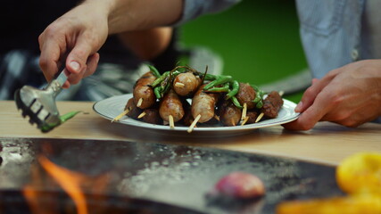 Unknown guy putting vegetables in plate outside. Man chef using forceps outdoors