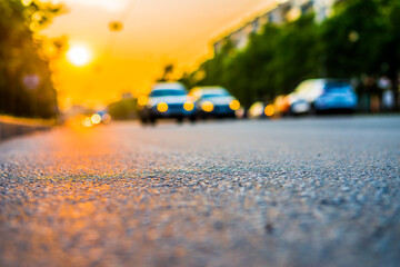 Sunset in the city, the cars driving on the road. Close up view from the asphalt level